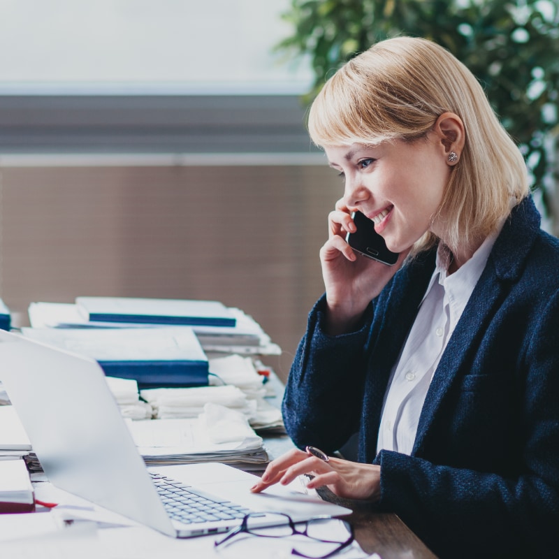 Woman on a phone looking at a laptop