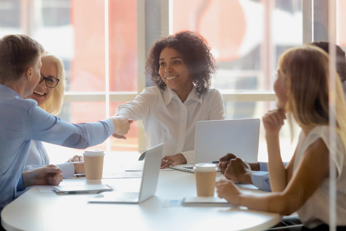 woman shaking hands with man at table during business meeting