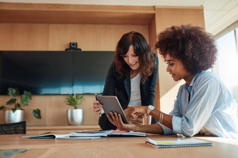 two women talking at meeting pointing at tablet