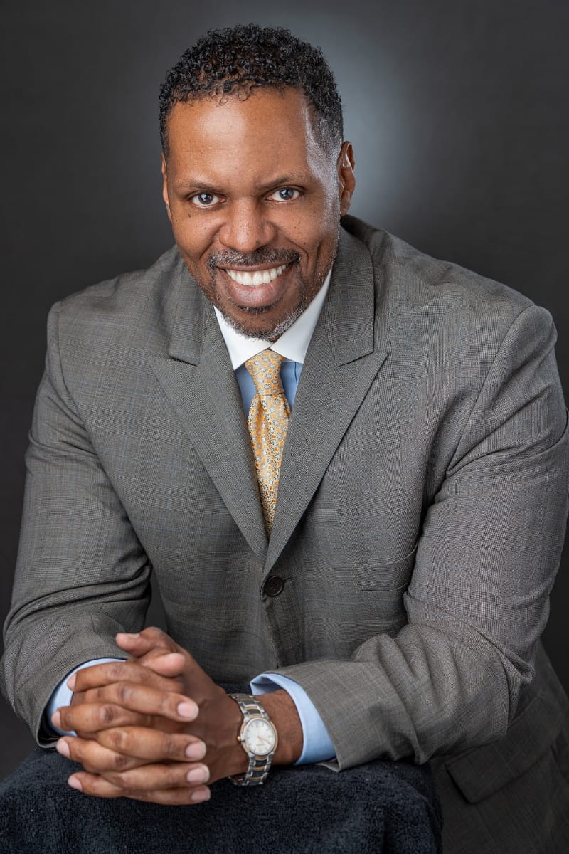 Headshot of Lance Butler - smiling man with goatee and gray suit